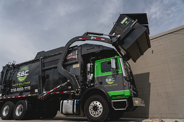 A dump truck lifting a front loader into the air, preparing to empty its contents.